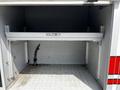 An empty storage compartment of a 2009 Ford F-550 featuring a flat shelf and metal brackets