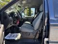 A 2014 Ford F-250 SD interior view showing the front seats and dashboard with gray upholstery and a thank you mat on the floor