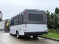 A white 2020 Chevrolet Express bus with large windows and rear lights visible is parked on a wet surface