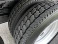 Close-up of the tires of a 2016 Isuzu NQR showing the tread pattern and rubber texture with multiple tires stacked together