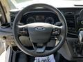 The interior steering wheel of a 2023 Ford Transit featuring controls for audio and cruise settings with a Ford emblem in the center