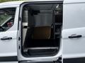 A 2014 Ford Transit Connect with an open side door revealing an empty cargo area and shelving installed inside