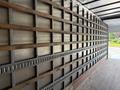 An empty cargo space of a 2022 International MV607 truck featuring vertical metal and wooden supports along the walls
