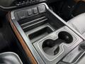 Center console of a 2017 Chevrolet Silverado 1500 featuring two cup holders and storage compartments with black and wood trim