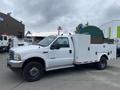 A white 2003 Ford F-450 SD with a utility bed featuring storage compartments on both sides and a black wheel rim