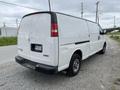 A white 2014 GMC Savana van parked with a sliding side door and empty cargo area