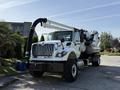 A 2013 International 7400 truck with a large suction hose and tank mounted on the chassis designed for vacuum and cleaning tasks