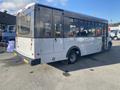 A 2018 Chevrolet Express shuttle bus with large windows and a white exterior is parked, showcasing its side and rear design