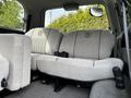 Interior view of a 2003 Mitsubishi 7 Passenger Van showing two rows of gray upholstered seats with a central armrest and seatbelt visible