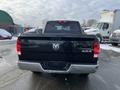 A black 2015 RAM 1500 truck viewed from the rear with the tailgate down and the RAM logo prominently displayed in the center