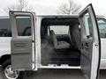 A 2011 Ford Econoline van with its side doors open revealing a spacious interior with two front seats and a bench seat in the middle