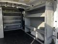 A 2017 Ford Transit van interior featuring empty shelving units along the sides with a spacious, bare floor