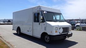 A white 2011 Ford Econoline van with a boxy shape and large front windshield parked with no visible markings on the side