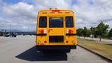 A yellow 2014 Freightliner Thomas Bus Diesel viewed from the rear featuring emergency lights and doors with a cautionary sign