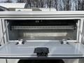 A rear view of a 2016 Ford F-350 SD truck bed with an open toolbox showing a metal shelf and locking mechanism inside