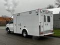 A white 2016 Chevrolet Express with a large cargo area and rear entrance doors emitting exhaust from the back