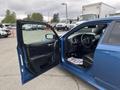 A blue 2022 Dodge Charger with the driver's door open showing the interior features including seats and dashboard