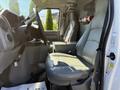 Interior of a 2011 Ford Econoline with two leather seats a steering wheel and a console in the front cabin area