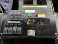 A dashboard control panel featuring multiple switches and a battery indicator with wires visible behind an opening
