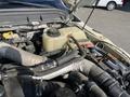Close-up of the engine compartment of a 2015 Ford F-450 SD showing various hoses and components including a coolant reservoir and battery