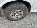 A close-up of a tire on a 2014 GMC Savana showing a rugged tread pattern and a silver wheel with a central logo