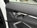 Interior door panel of a 2024 Audi Q3 featuring a sleek design with control buttons for windows and locks
