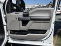 The interior door panel of a 2018 Ford F-150 featuring a gray color scheme with a handle and window controls