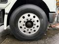 A close-up view of a large tire on a 2003 Freightliner FL70 showing detailed tread patterns and multiple lug nut holes on a metallic wheel rim