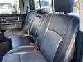 A black leather interior of a 2017 RAM 1500 showing the back seat with two seat belts and a textured pattern on the seat fabric