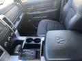 Interior view of a 2011 RAM 1500 showing the front seat gear shift console and armrest with Dodge logo and cup holders