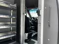 A 2023 Mercedes-Benz Sprinter with an open door revealing the driver's seat and metal shelving inside the cargo area