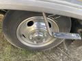 A close-up of a silver wheel rim with a black tire attached to a 1987 Chevrolet Fleetwood Pace Arrow