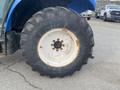 A large tractor tire with a white rim and visible wear is shown with a rugged tread pattern and some rust on the rim