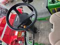 The steering wheel and operator controls of a 2014 John Deere 1585 Terrain Cut mower with a comfortable seat and various control levers