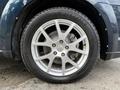 Silver alloy wheel of a 2013 Dodge Journey featuring five spokes and a Michelin tire placed on a dark vehicle