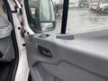 A close-up view of the driver's side door of a 2018 Ford Transit featuring a gray interior panel with controls and a rain-speckled window