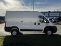 A white 2021 RAM Promaster van is parked on the street showcasing its cargo area and passenger side profile with a simple and utilitarian design