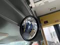 A circular mirror mounted inside a vehicle reflecting the interior with blue seats and a yellow frame