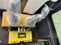A yellow control panel with two joystick levers covered in plastic and a yellow toolbox labeled "TOOL'S BOX" positioned on a textured black surface