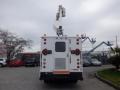 A white 2002 International 4700 truck with a mounted bucket lift on the roof facing backward and featuring three rear lights and a rear access panel