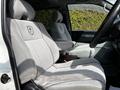 Interior view of a 2003 Mitsubishi 7 Passenger Van showing two light gray front seats with armrests and logos on the headrests