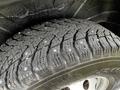 Close-up of a winter tire with deep tread patterns and metal studs designed for enhanced grip on ice and snow mounted on a RAM Promaster vehicle