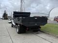 A 2021 Ford F600 truck with a flatbed and a raised tarp cover parked on a street