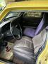 Interior view of a 1978 Volvo 244 featuring a yellow exterior with purple and gray upholstery in the front seats and an old carpet on the floor