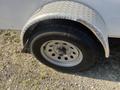 A close-up of a wheel and fender of a 2020 Mirage Enterprises 12 Foot Cargo trailer featuring a metal diamond plate fender and a black tire with silver wheel rim