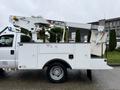 A 2012 Ford F-450 SD equipped with a Terex bucket lift attached to the bed, designed for utility work, with a white service body and large wheels