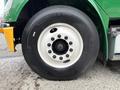 A close-up view of a 2015 Freightliner M2 106 tire showing a black rubber tire with light-colored rim and multiple bolts on the rim