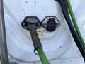 A close-up of a Freightliner Cascadia's fuel inlet and electrical connection with a green hose attached and caution label visible