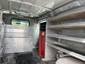 Interior of a 2009 Ford Econoline van featuring metal shelving and storage compartments with a red cabinet and rubber floor mats