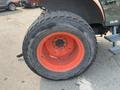 A large tire from a 2010 Kubota M6040 tractor featuring a rugged tread pattern and an orange rim